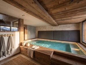Ein Holzinnenraum mit Whirlpool, Handtüchern und Bergblick.
