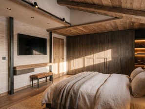 Een moderne slaapkamer met een groot bed, een inbouwkast en een flatscreen televisie aan de muur.