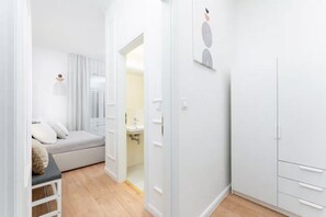 A modern, minimalist bedroom with a bed, a bedside table, and a wardrobe.