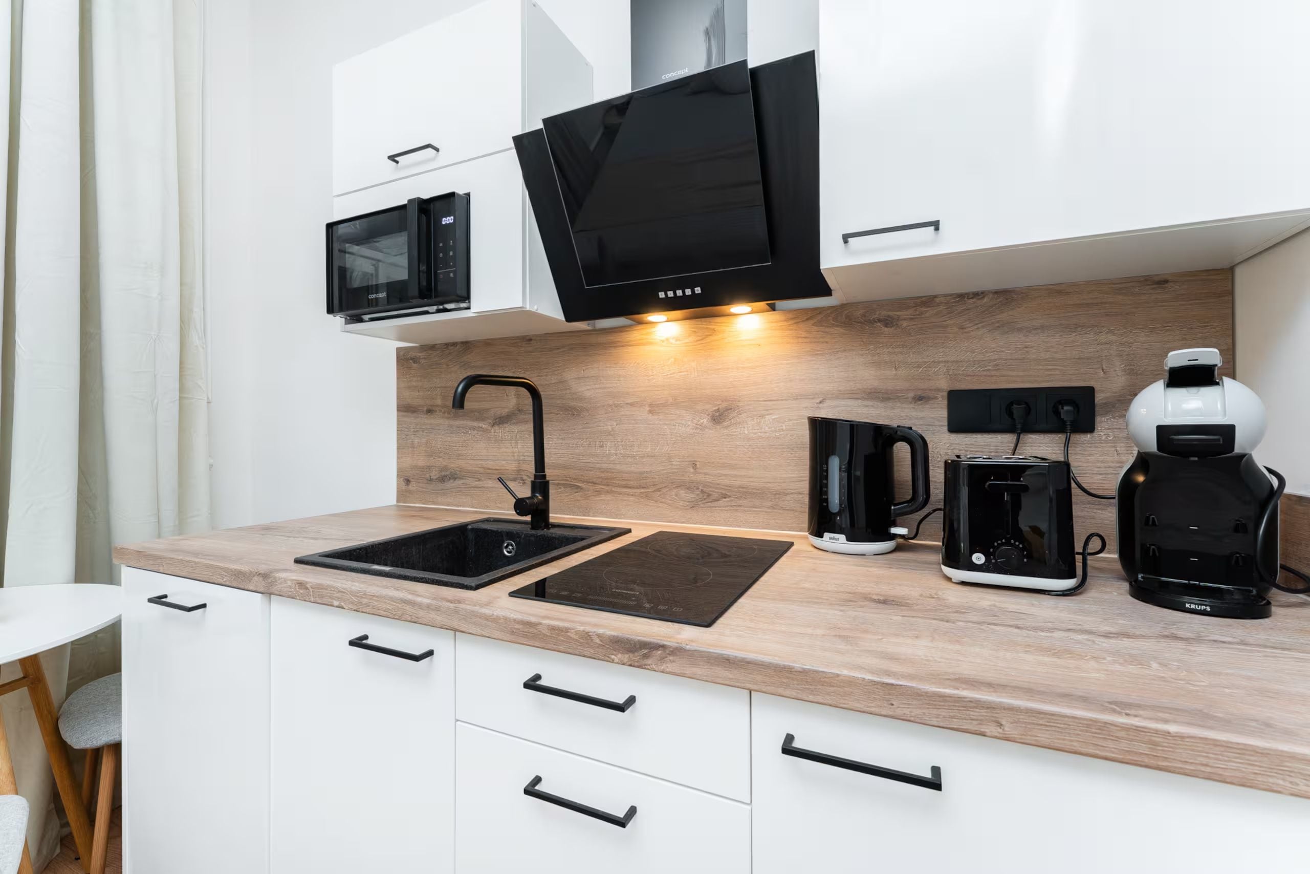 A modern kitchen with a sink, a microwave, a coffee maker, and a toaster.