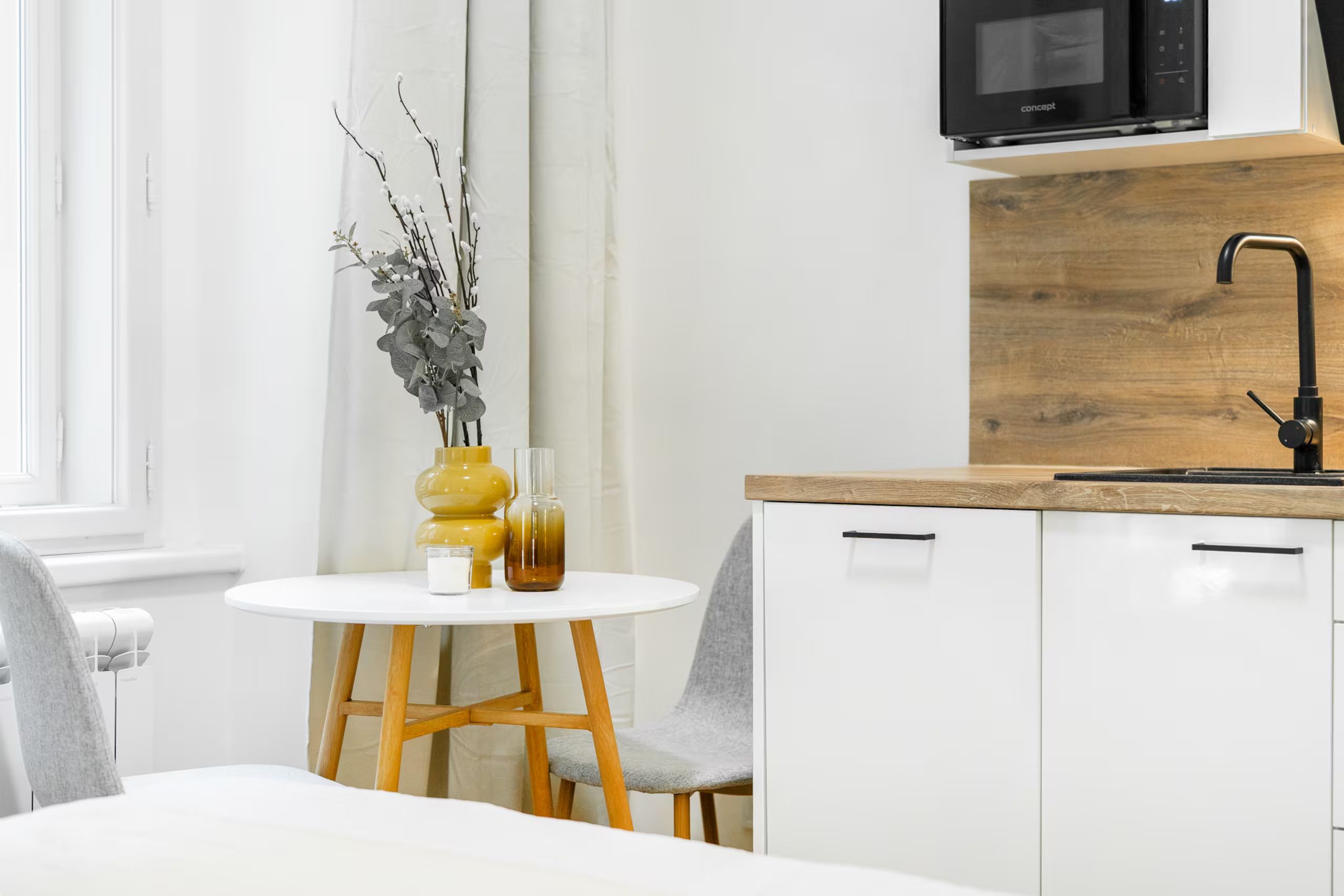 A modern kitchen with white cabinetry, a wooden countertop, and a black faucet.