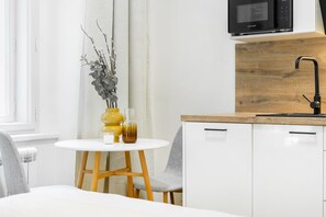 A modern kitchen with white cabinetry, a wooden countertop, and a black faucet. - Modern studio with AC in the heart of Prague (Praha)