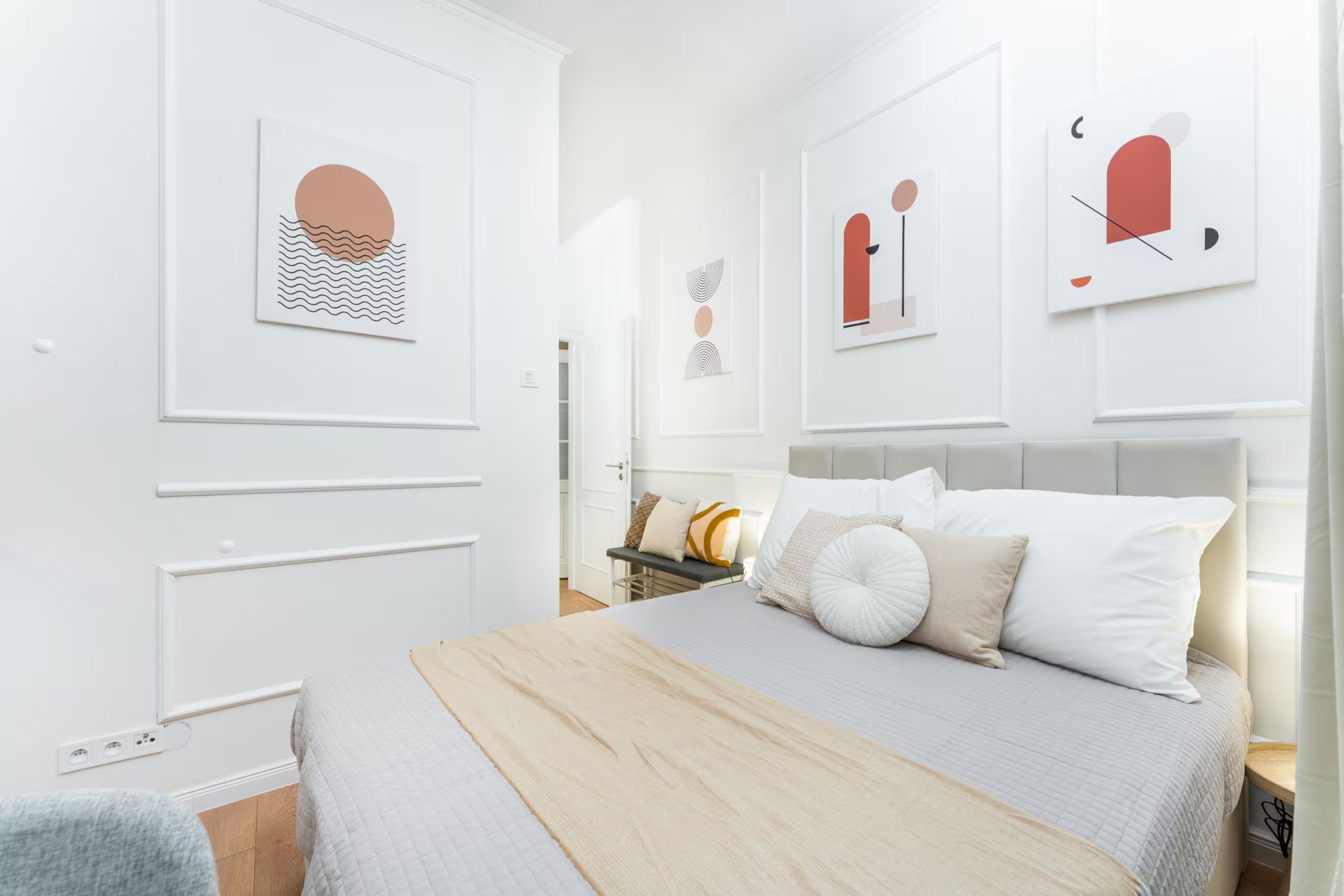 Ein modernes Schlafzimmer mit einem großen Bett, einem Nachttisch und Kunstwerken an den Wänden.