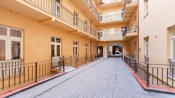 A multi-story building with balconies, a cobblestone street, and a central archway.