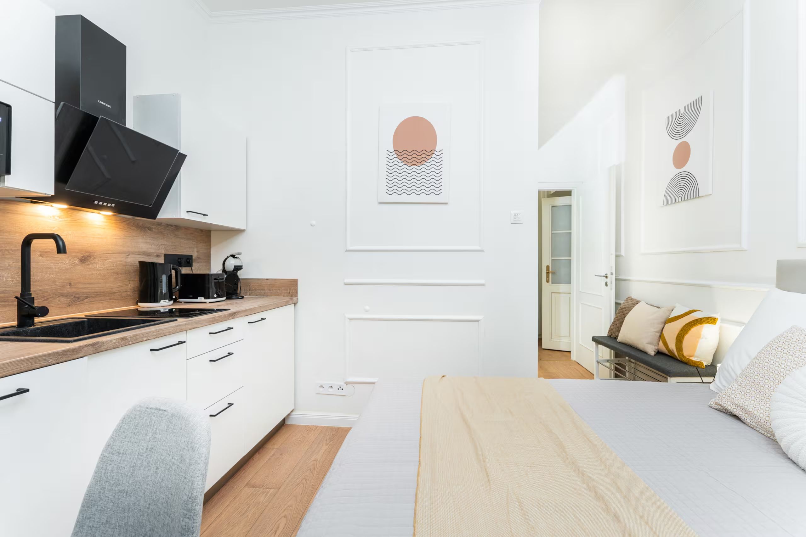 A modern, minimalist bedroom with a bed, bedside table, and a view into the adjacent bathroom.