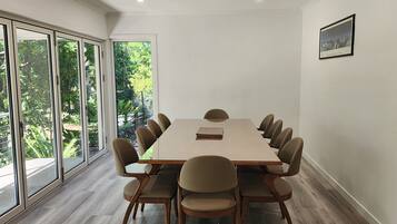 A conference room with a long table and chairs, large windows, and a framed picture on the wall.