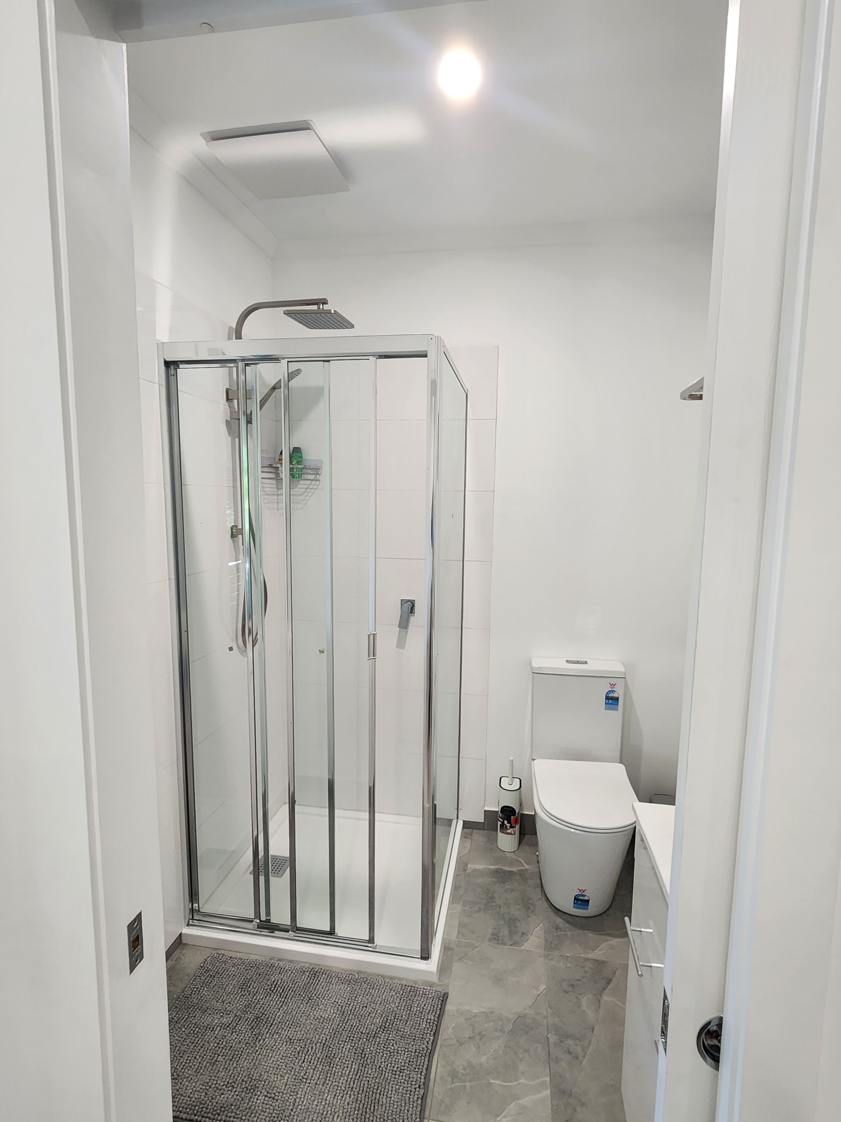 A modern bathroom with a glass-enclosed shower, a toilet, and a sink.
