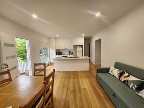A modern kitchen with white cabinets, a central island, and a dining area with wooden furniture.