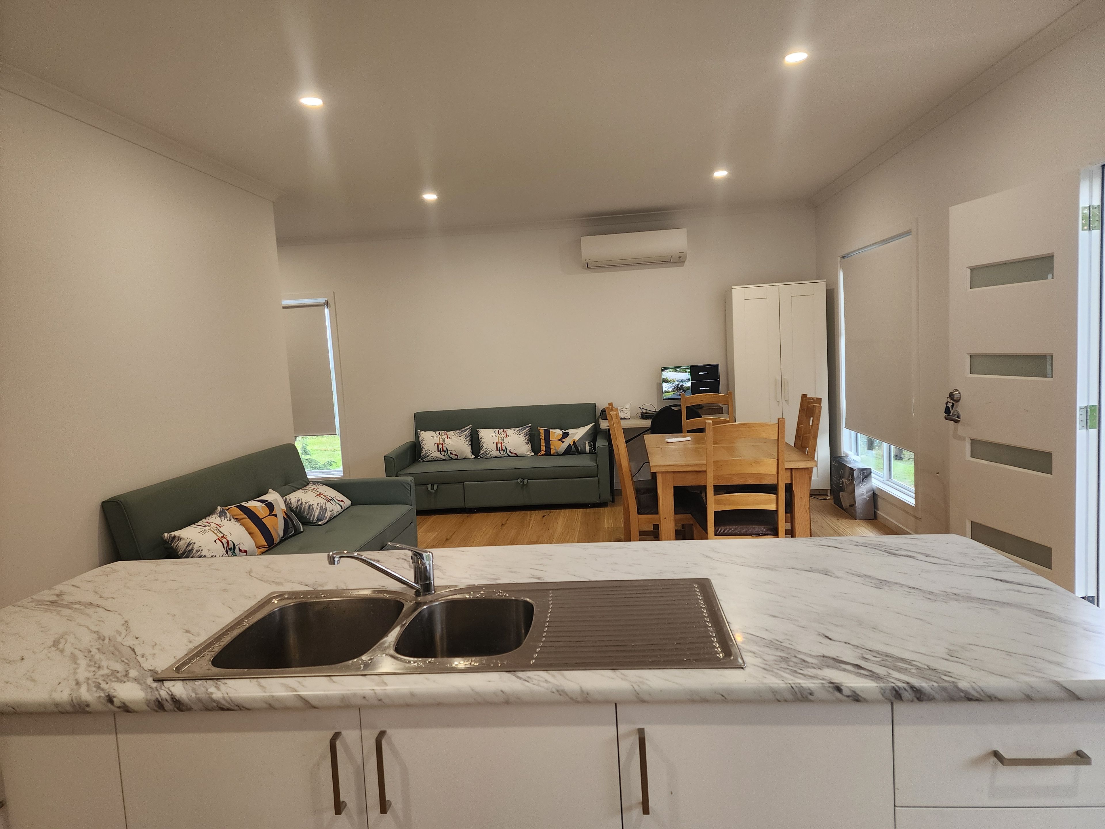 Une cuisine moderne dotée d’un plan de travail en marbre, d’un évier et d’un coin repas avec une table et des chaises en bois.