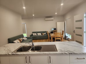 Una cuina moderna amb taulell de marbre, una barra i una zona menjador amb taula i cadires de fusta.