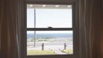 Una habitación con ventana que da a una calle, cortinas y una cama con cabecero.