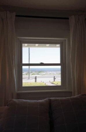 Une chambre avec une fenêtre donnant sur une rue, des rideaux et un lit avec une tête de lit.