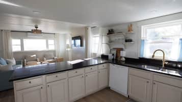 A modern kitchen with white cabinets, a black countertop, and a built-in dishwasher.