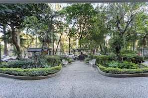 A paved pathway leading through a landscaped area with benches and trees.