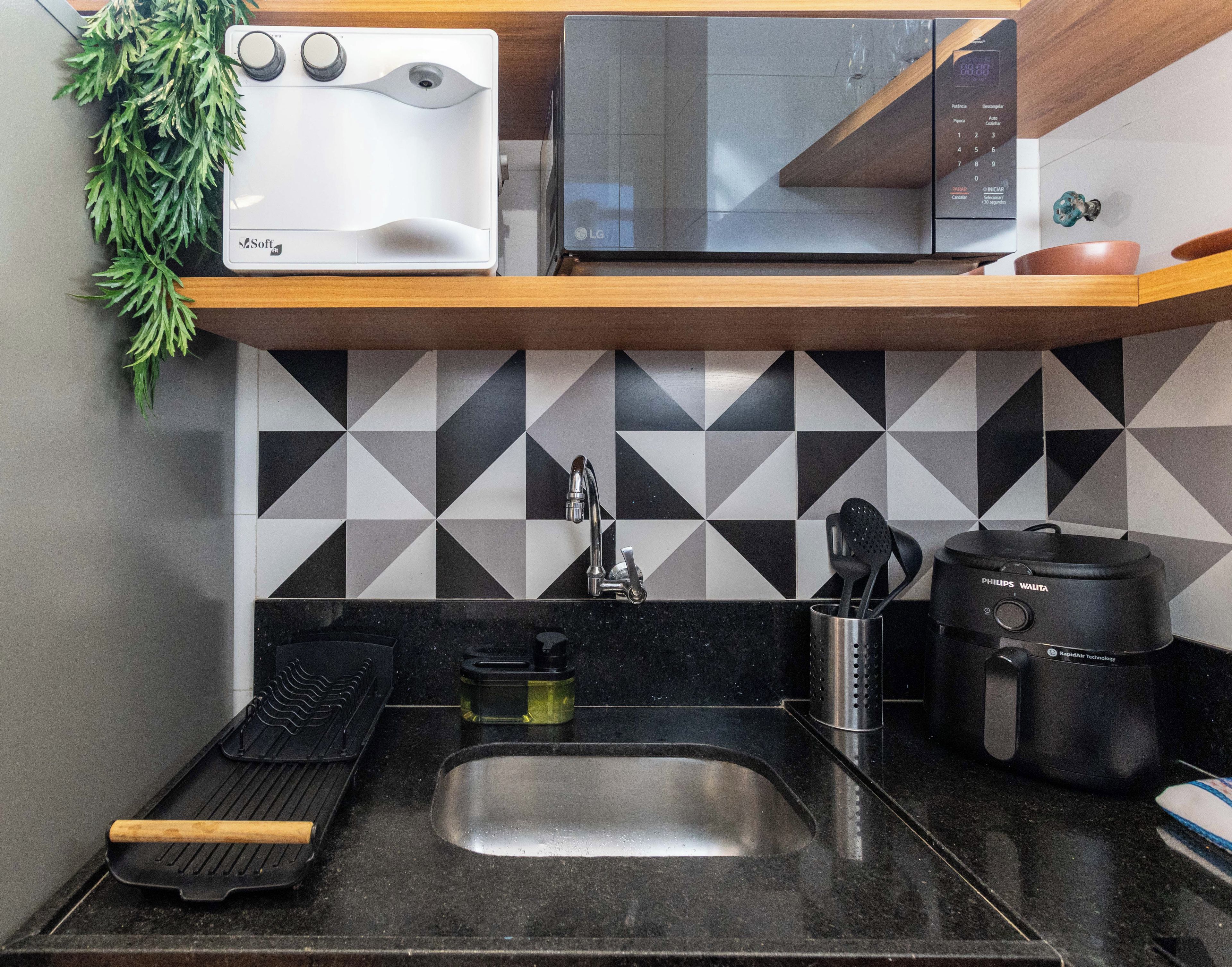 A kitchen with a microwave, toaster, sink, and a coffee maker.