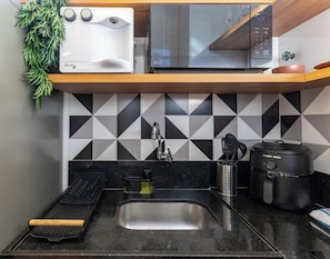 A kitchen with a microwave, toaster, sink, and a coffee maker.