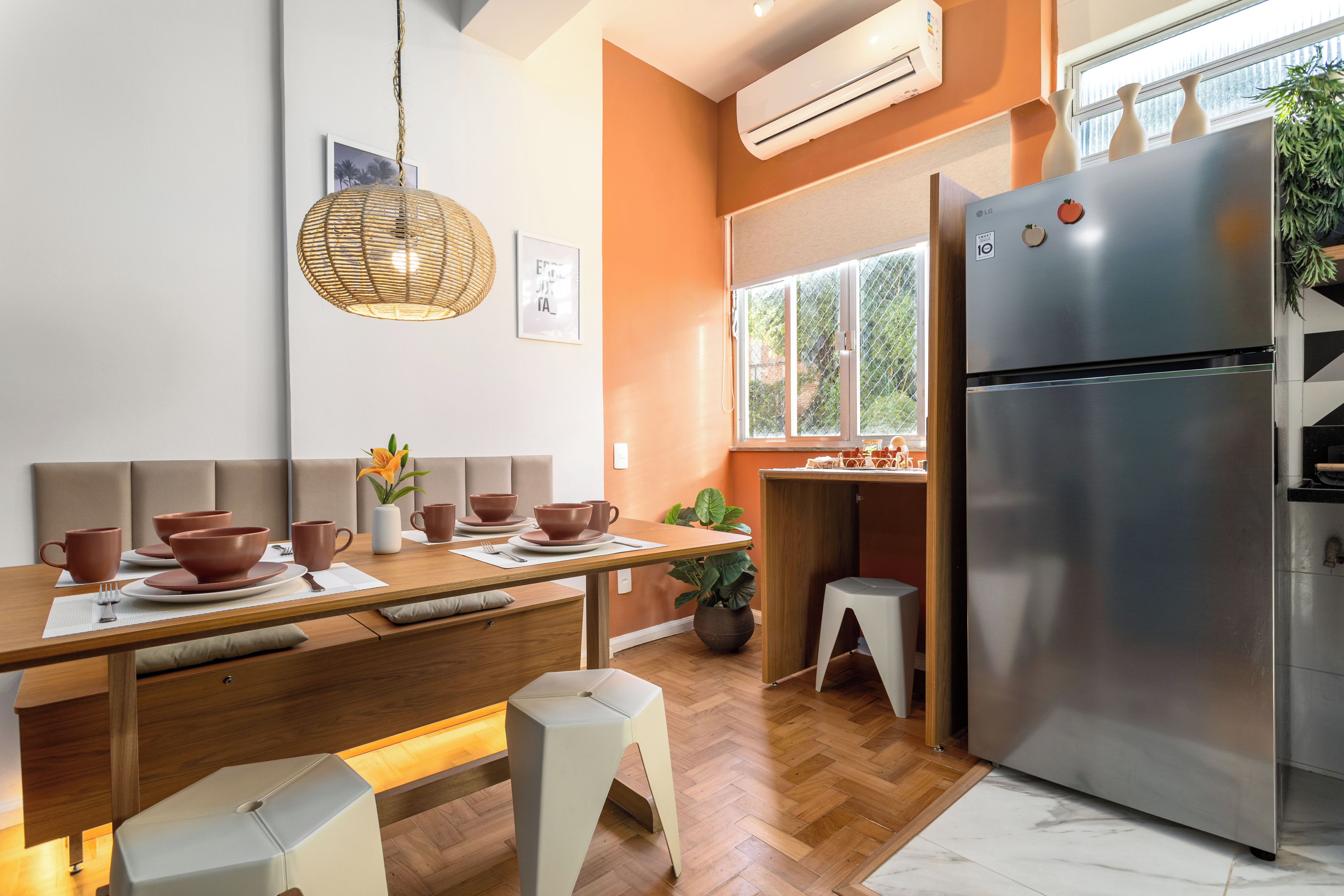 Une cuisine moderne avec un réfrigérateur en acier inoxydable, une table à manger en bois et un luminaire suspendu.