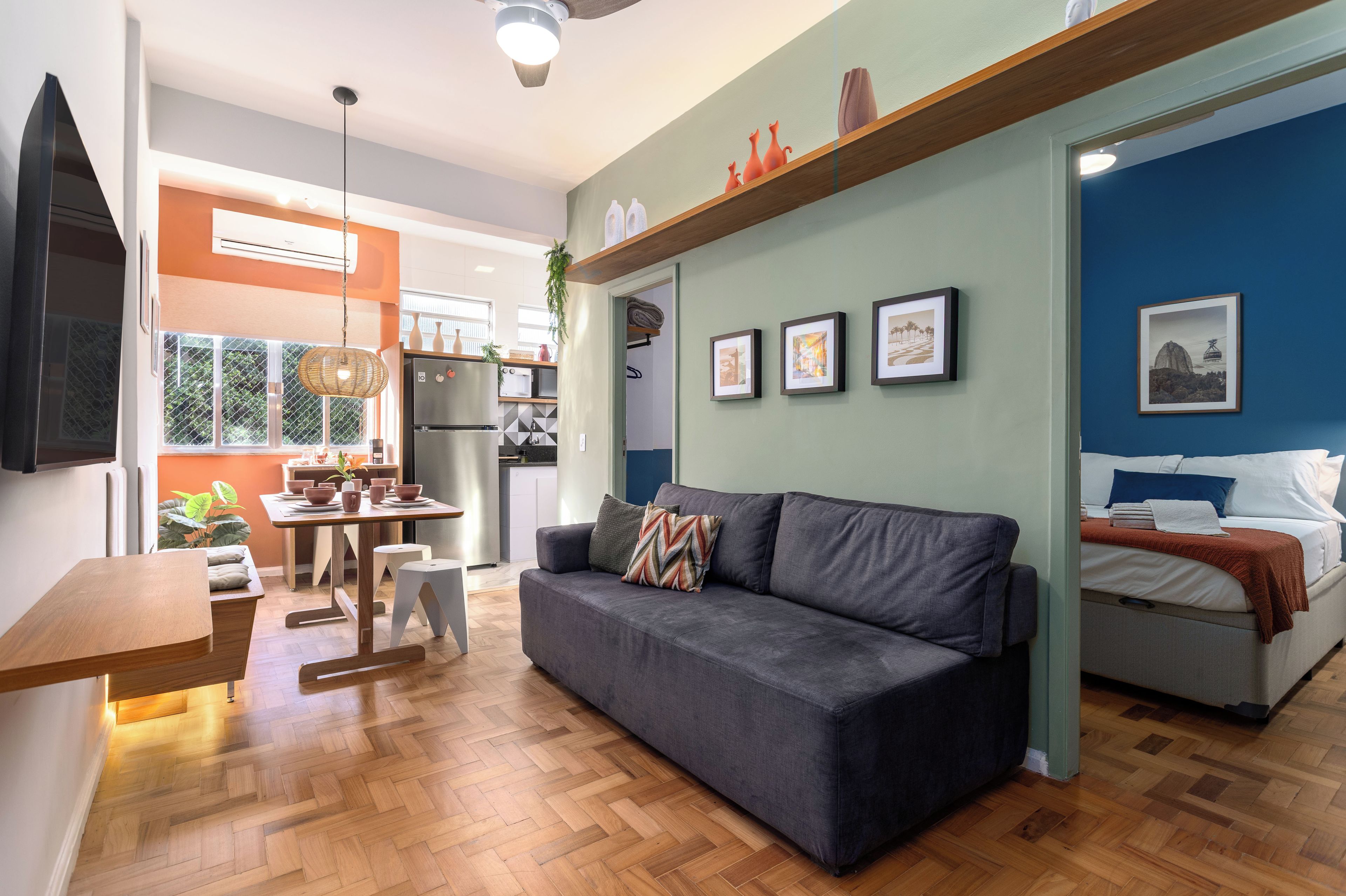 A modern living space with a grey sofa, a dining area, and a kitchen.