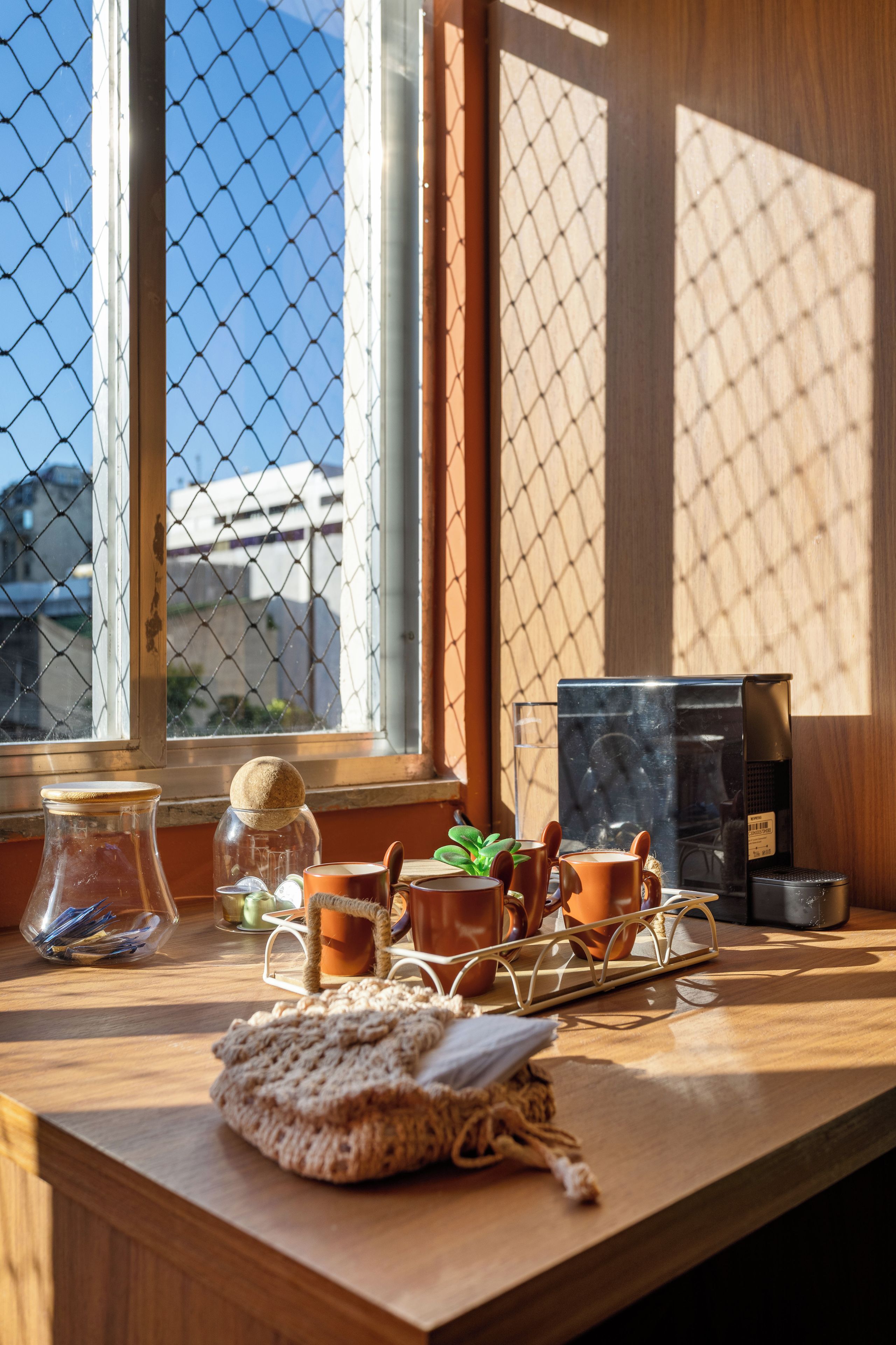 Una mesa de madera con una cafetera, un tarro de vidrio y una olla de cerámica.
