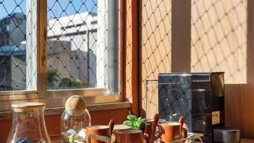 Una mesa de madera con una cafetera, un tarro de vidrio y una olla de cerámica.
