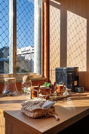 Una mesa de madera con una cafetera, un tarro de vidrio y una olla de cerámica.