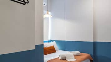 Un dormitorio con una cama, una lámpara colgante, un ventilador de techo y piso de madera.