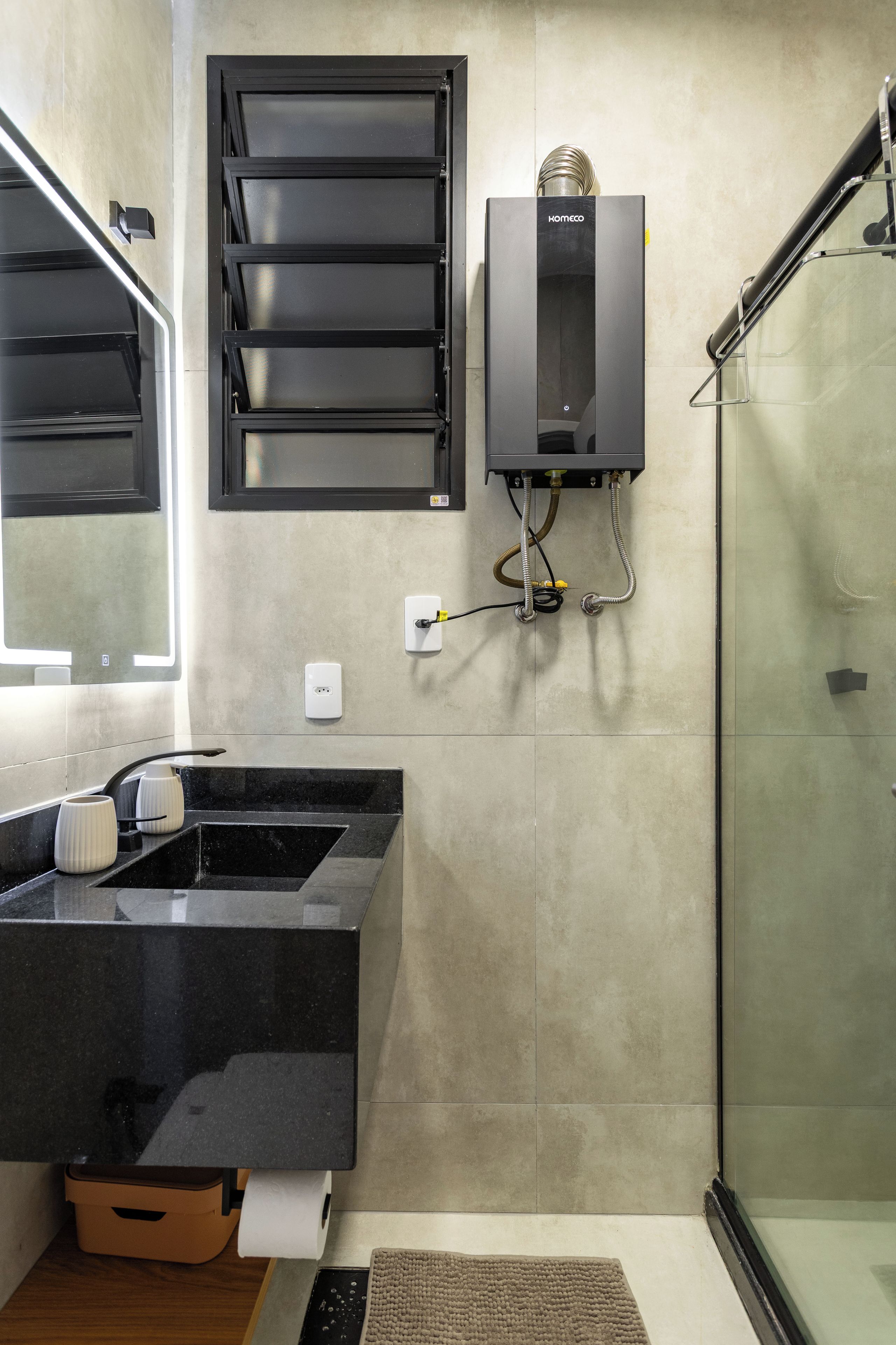 A modern bathroom with a black sink, a glass shower enclosure, and a wall-mounted water heater.