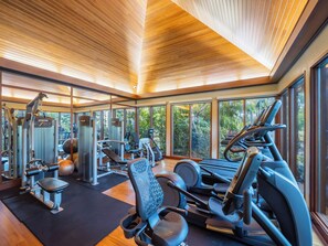 A gym with various exercise equipment, large windows, and a wooden ceiling. - Waikiki 2BR Condo | 2 King Beds, Parking, Lanai & Ocean View (Honolulu)