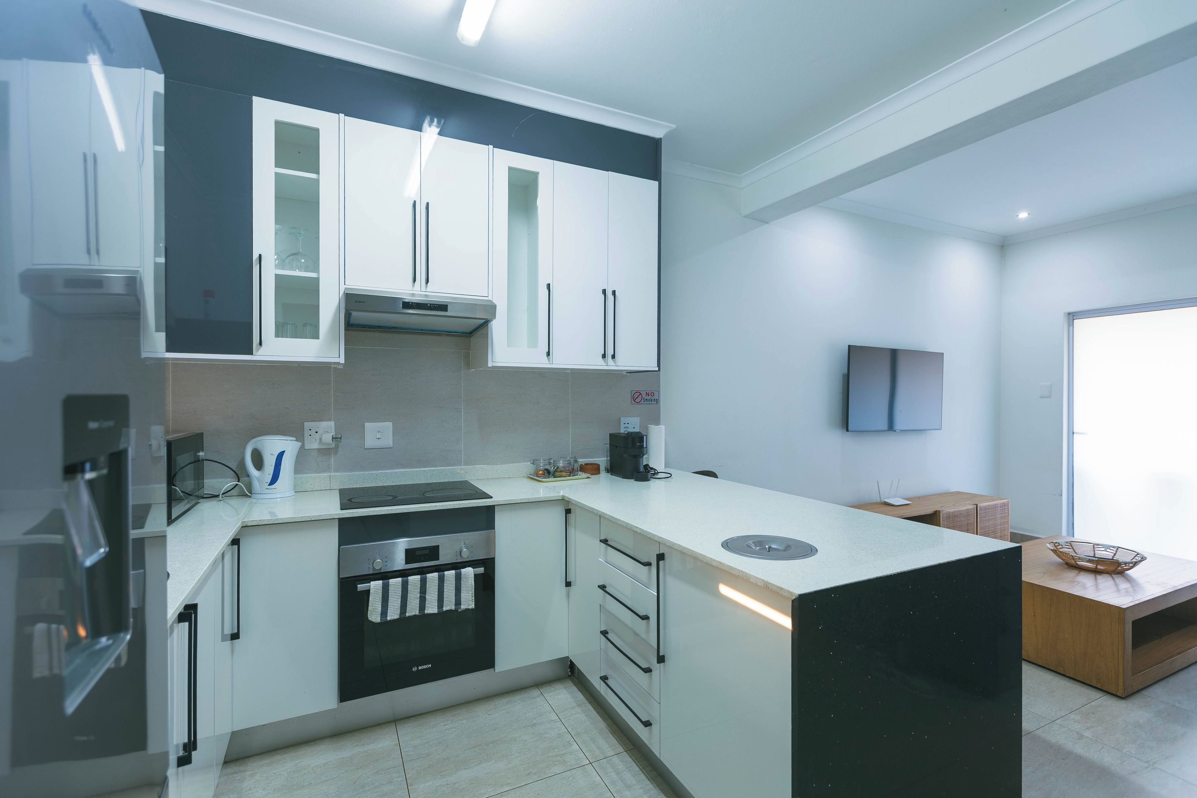 A modern kitchen with white cabinets, a Bosch dishwasher, and a built-in oven.