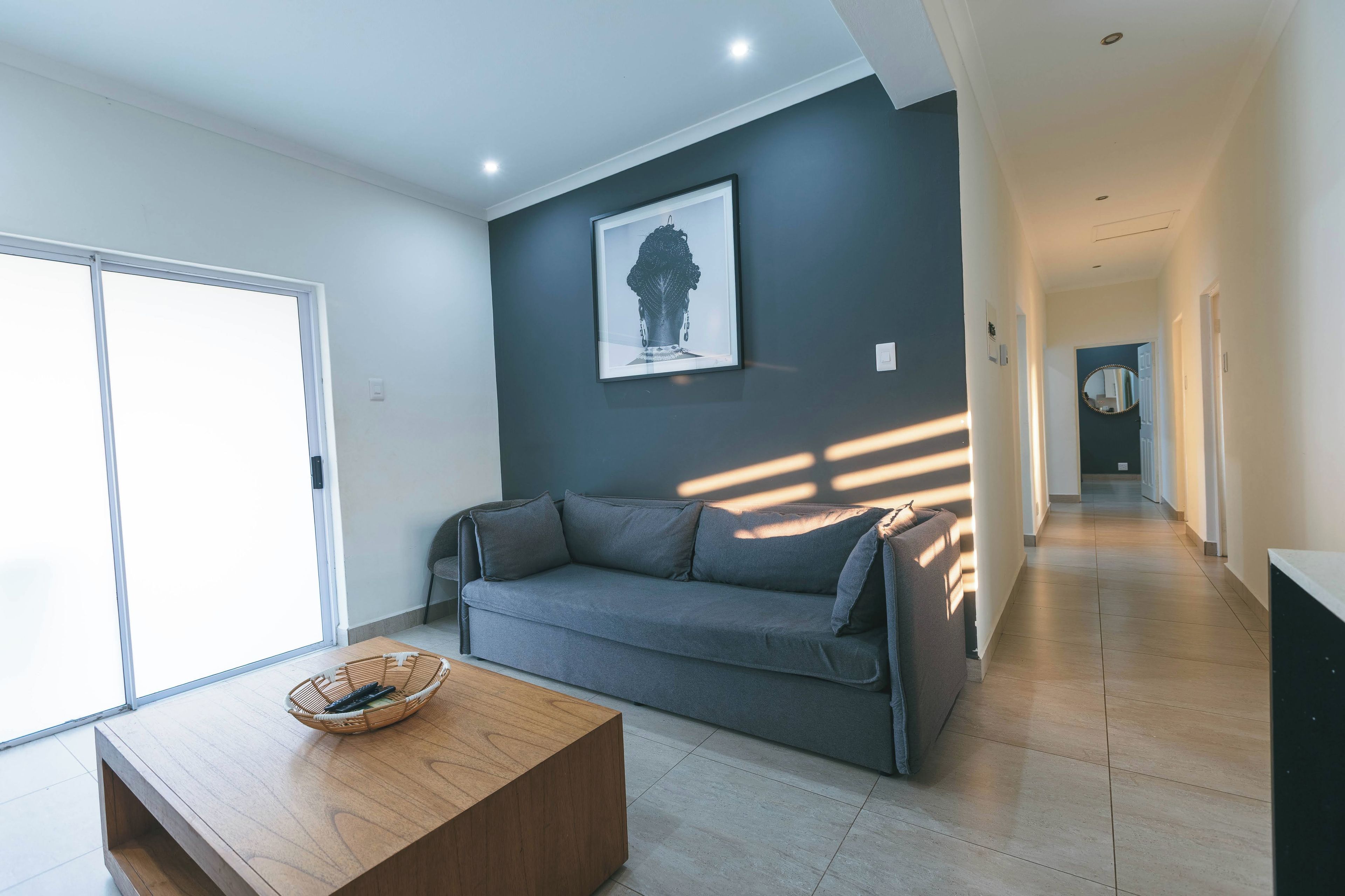 Un salon moderne avec un canapé gris, une table basse en bois et une œuvre d’art encadrée accrochée au mur.