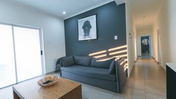 Un salon moderne avec un canapé gris, une table basse en bois et une œuvre d’art encadrée accrochée au mur.