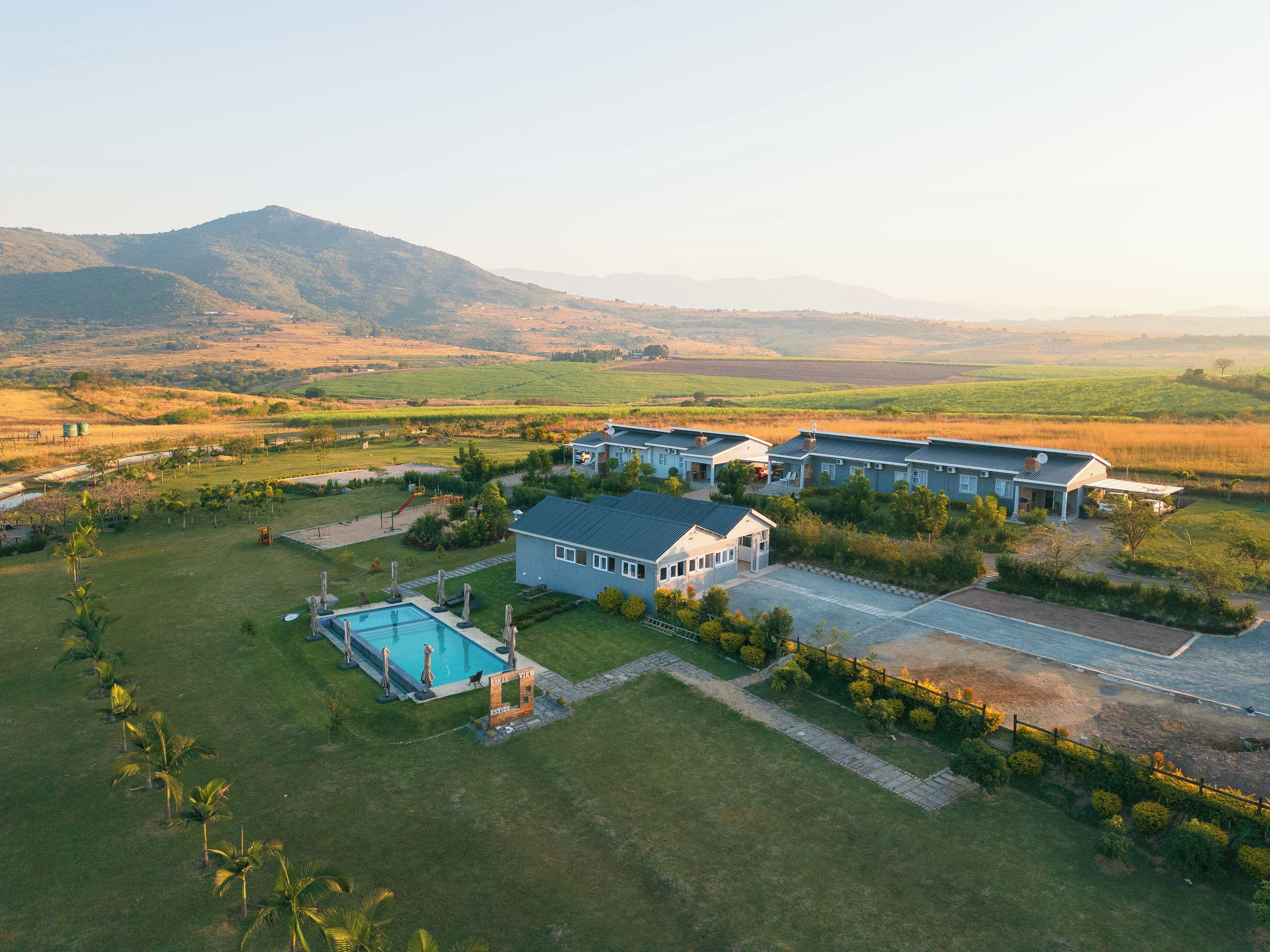A residential area with multiple houses, a swimming pool, and a view of distant hills.