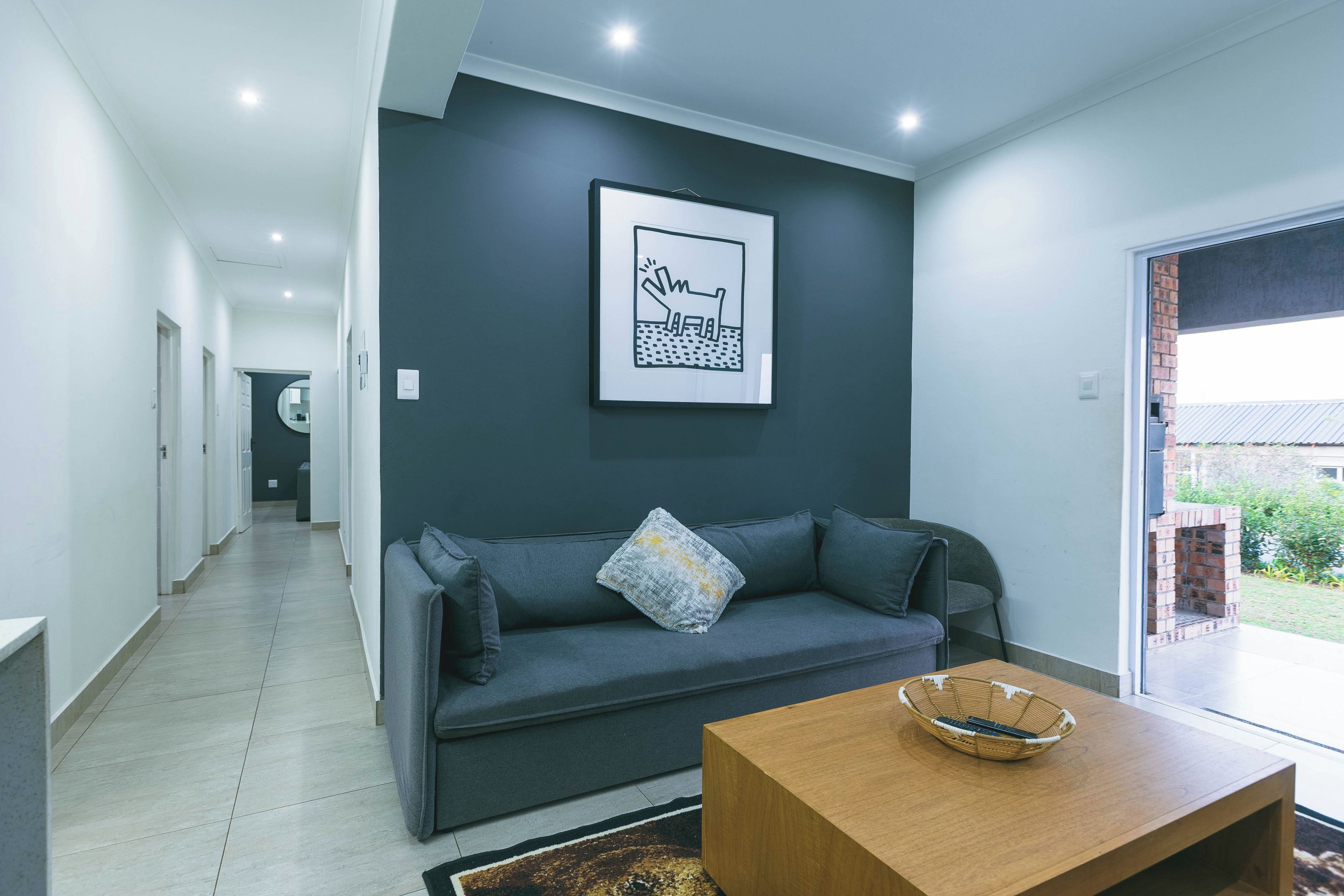 A modern living room with a grey sofa, a wooden coffee table, and a framed artwork on the wall.