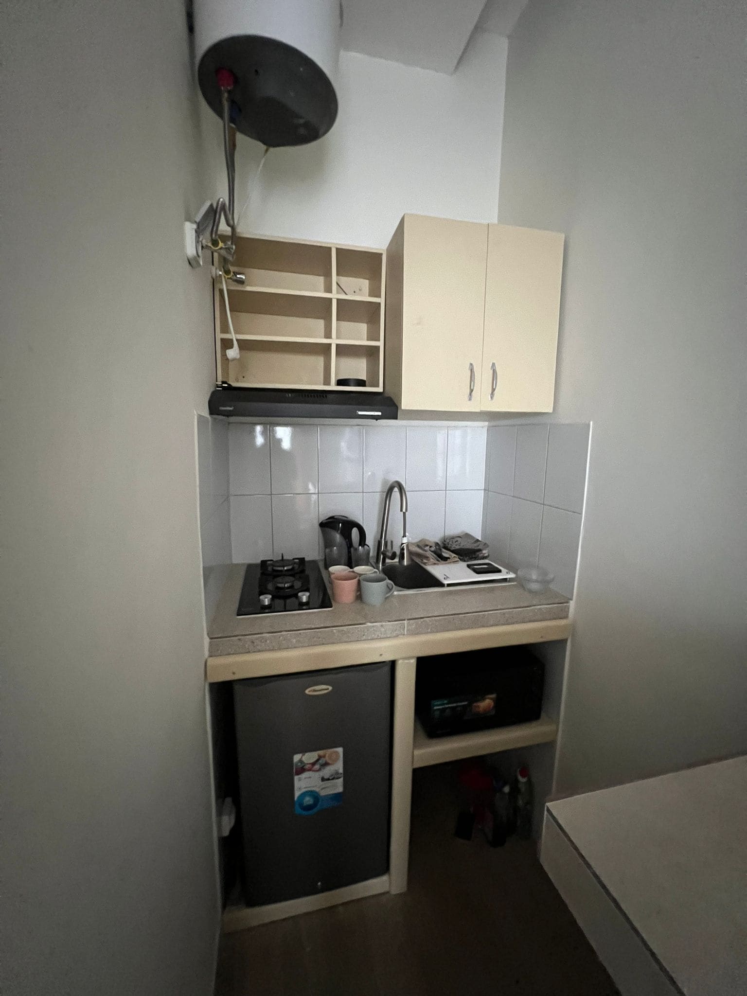 Een kleine keuken met een gasfornuis, gootsteen en kastjes.