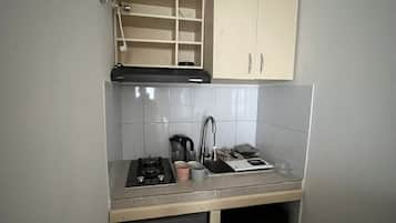Een kleine keuken met een gasfornuis, gootsteen en kastjes.