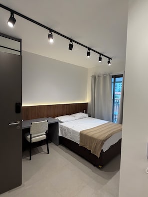A modern hotel room with a bed, desk, chair, and a view of the outside. - Studio apartment next to the Morumbi Shopping Mall and the Brooklin subway station. (São Paulo)