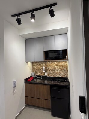A compact kitchen with a microwave, stove, and sink. - Studio apartment next to Morumbi Shopping Mall and Brooklin metro station. (São Paulo)