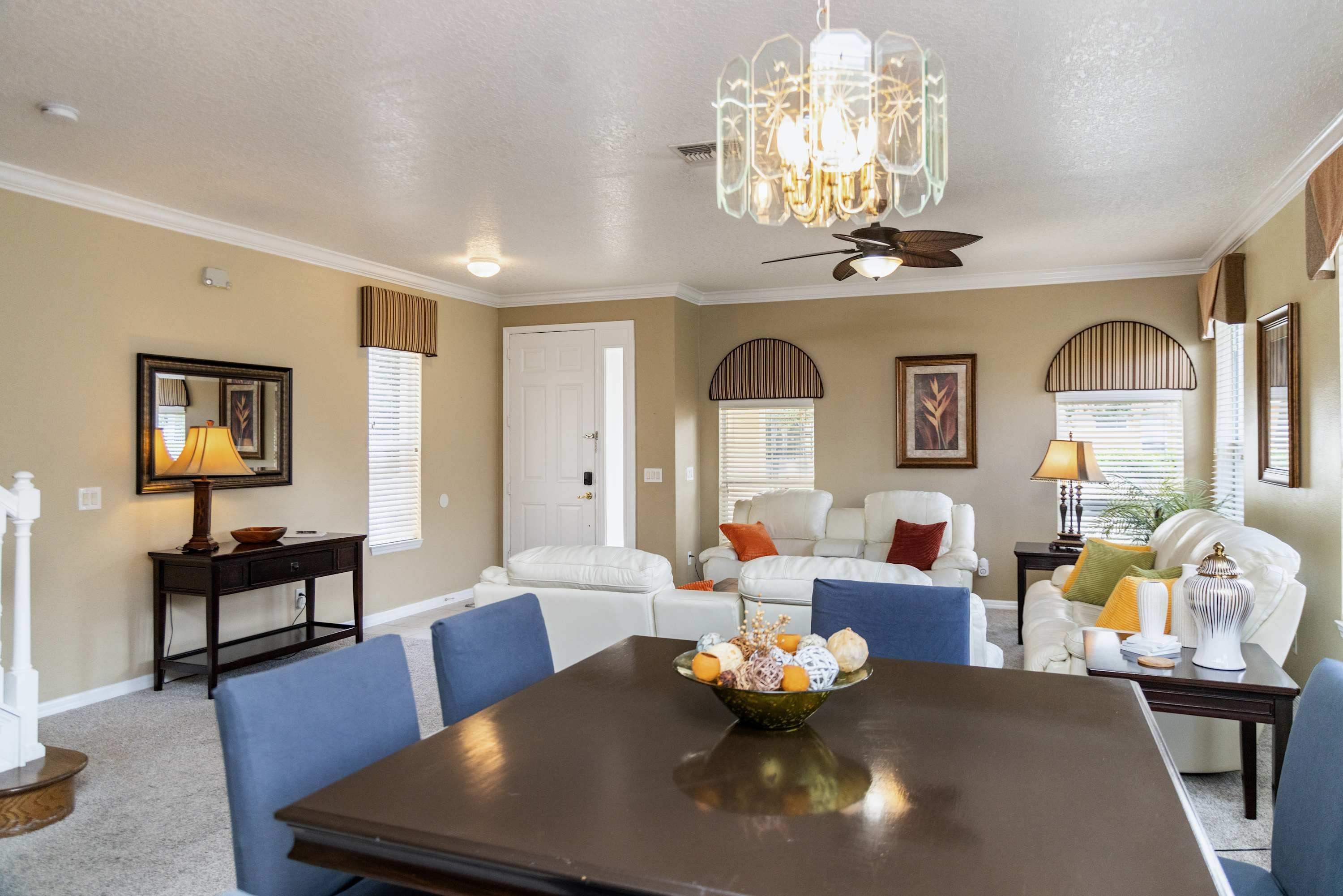 A dining area with a dark wooden table, blue chairs, and a chandelier.