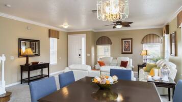 A dining area with a dark wooden table, blue chairs, and a chandelier.