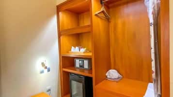 Un dormitorio con un armario de madera, una mesita de noche con un teléfono, un microondas y un mueble pequeño.