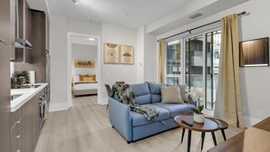 A modern apartment with a kitchen, a living area with a sofa and coffee table, and a large sliding glass door to the balcony. - StayToronto - Stylish 1BR Retreat, Sleeps 4 - Downtown Core (Toronto)