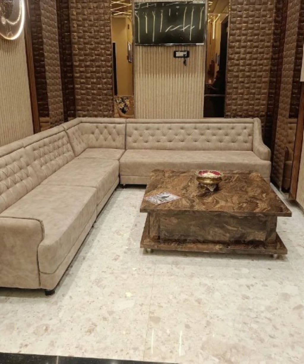 A beige sectional sofa and a marble coffee table in a room with brick-patterned walls and a modern design.