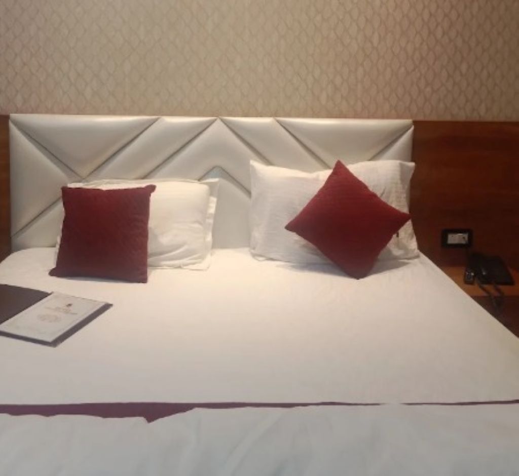 Une chambre d’hôtel avec un lit, deux oreillers, une table de chevet et une petite table d’appoint.