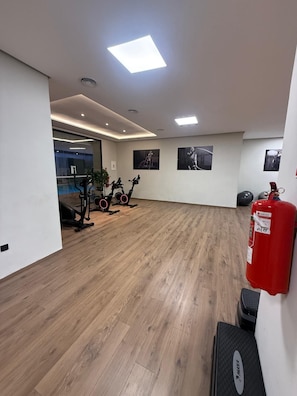 Ein geräumiges Zimmer mit Holzboden, Trainingsgeräten und einem Feuerlöscher.
