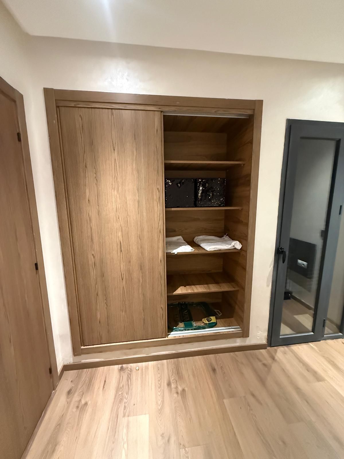 Une pièce avec une armoire en bois, une porte et un sol carrelé.