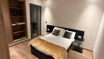 A modern bedroom with a bed, bedside tables, a wardrobe, and a door.