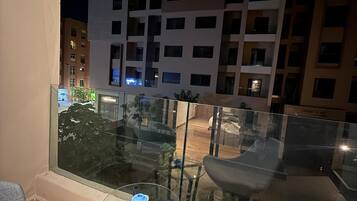 A balcony with a glass railing, a chair, and a small table.