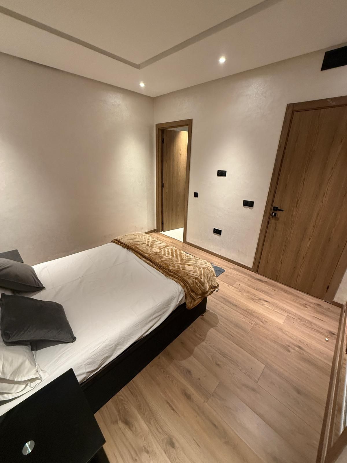 A bedroom with a bed, a wooden door, and a small window.