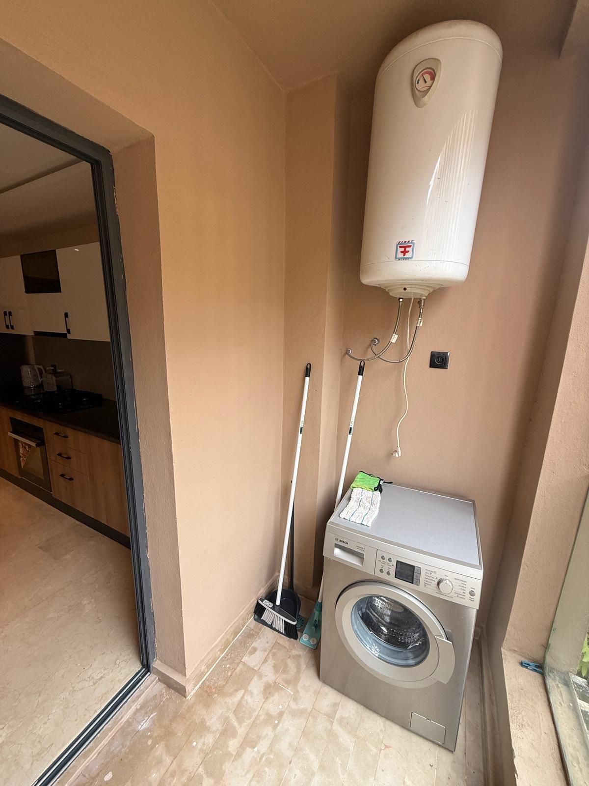 A laundry area with a Bosch washing machine, a mop, and a water heater.
