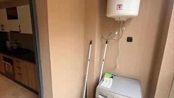 A laundry area with a Bosch washing machine, a mop, and a water heater.